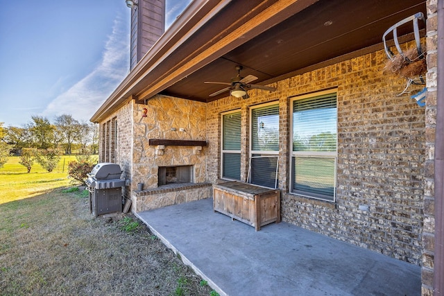 view of patio / terrace with ceiling fan, an outdoor stone fireplace, and grilling area