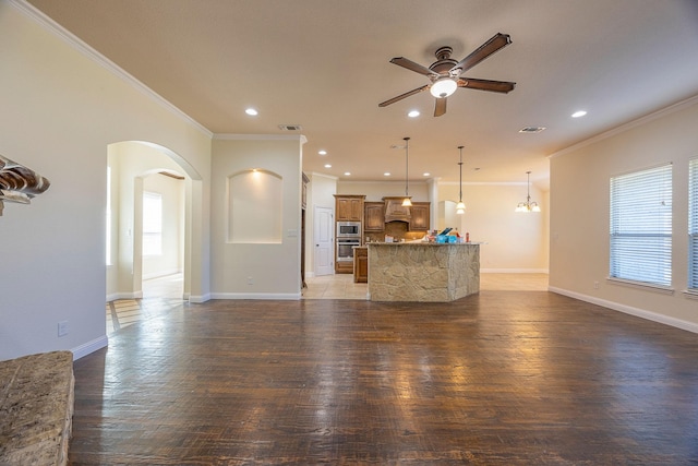 unfurnished living room with arched walkways, ceiling fan with notable chandelier, visible vents, baseboards, and light wood-style floors