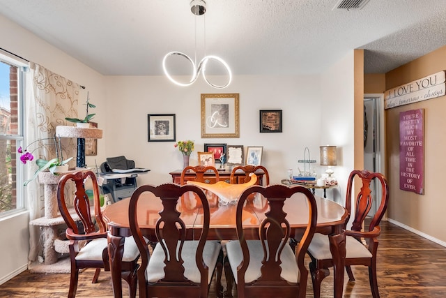 dining area featuring a textured ceiling, wood finished floors, visible vents, and baseboards