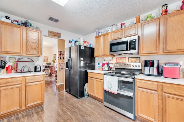 kitchen featuring light wood-style floors, appliances with stainless steel finishes, light countertops, and a textured ceiling