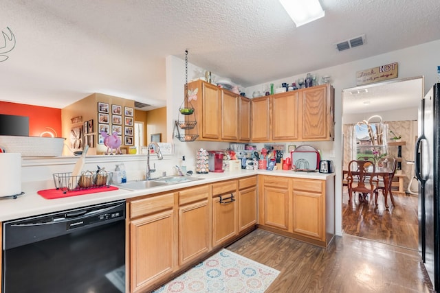 kitchen with light countertops, visible vents, a sink, wood finished floors, and black appliances