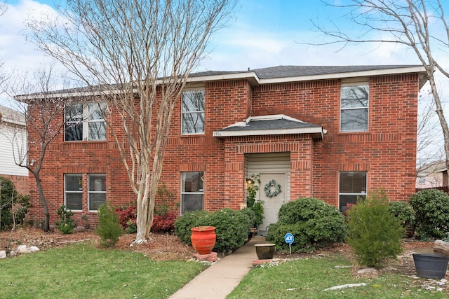 view of front of house featuring brick siding, a front lawn, and a shingled roof