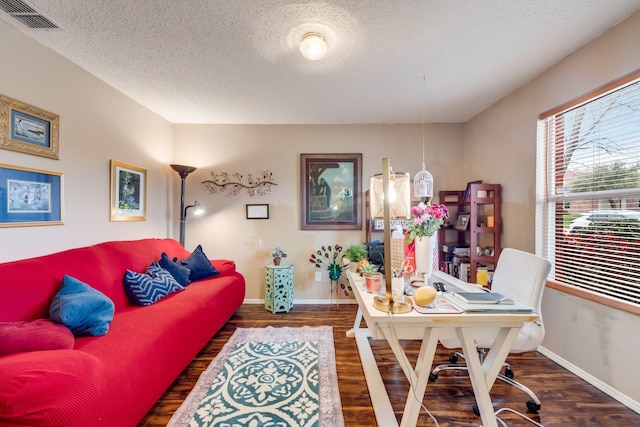 home office with baseboards, wood finished floors, visible vents, and a textured ceiling