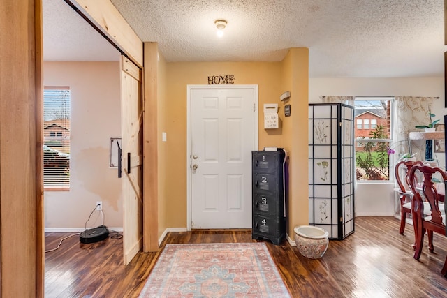 foyer with a textured ceiling, baseboards, and wood finished floors