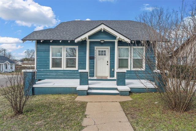 bungalow-style home with a shingled roof and a front lawn