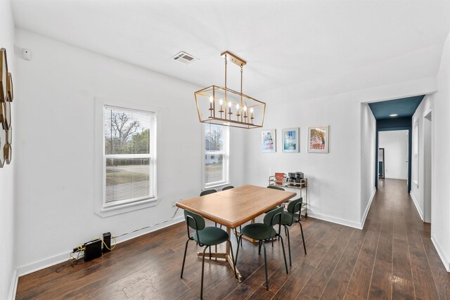 dining space featuring a chandelier, dark wood-style flooring, visible vents, and baseboards