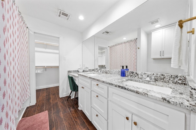 bathroom featuring double vanity, wood finished floors, a sink, and visible vents