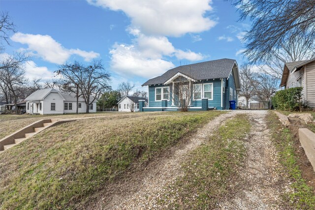 bungalow featuring driveway and a front lawn