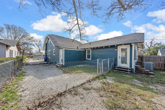 back of property with a shingled roof, entry steps, central AC, fence private yard, and driveway