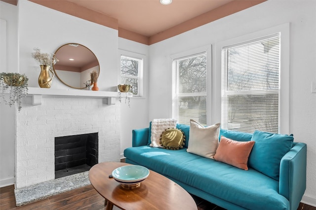 living room with a brick fireplace, baseboards, and wood finished floors
