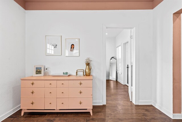 hallway featuring dark wood-style flooring and baseboards