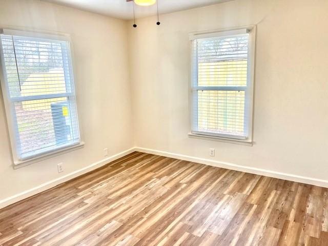 empty room featuring ceiling fan, plenty of natural light, wood finished floors, and baseboards