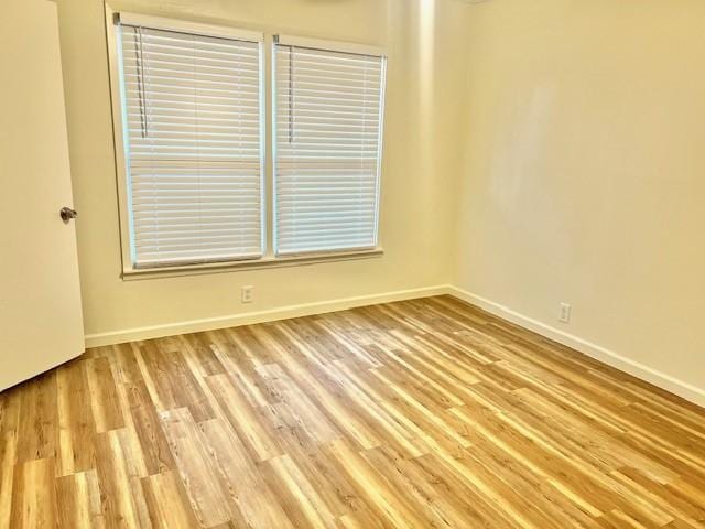 unfurnished room with light wood-type flooring and baseboards