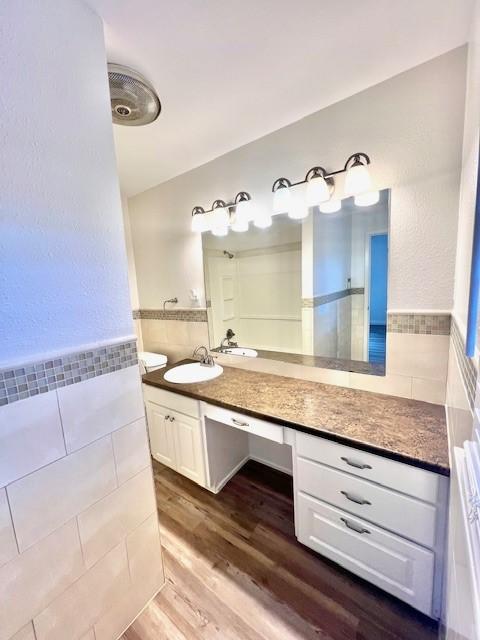 bathroom featuring vanity, wainscoting, wood finished floors, and tile walls