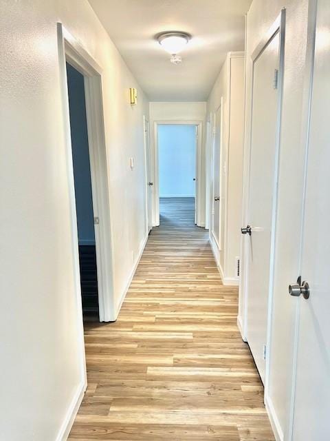 hallway with baseboards and light wood finished floors