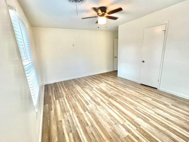 unfurnished bedroom featuring light wood finished floors, multiple windows, and baseboards