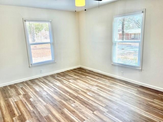 spare room with baseboards, a wealth of natural light, and wood finished floors