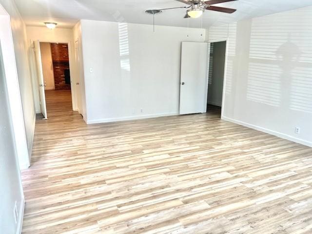 empty room featuring a ceiling fan, light wood-type flooring, and baseboards