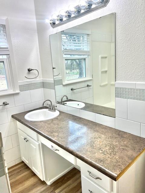 bathroom with a healthy amount of sunlight, tile walls, and wood finished floors