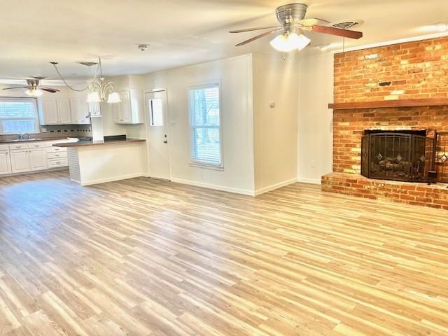 unfurnished living room featuring a fireplace, light wood-style flooring, and a healthy amount of sunlight