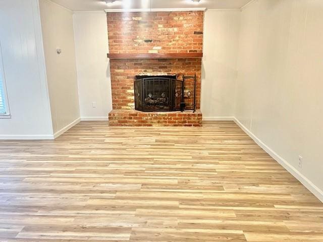 unfurnished living room featuring a fireplace, baseboards, crown molding, and wood finished floors