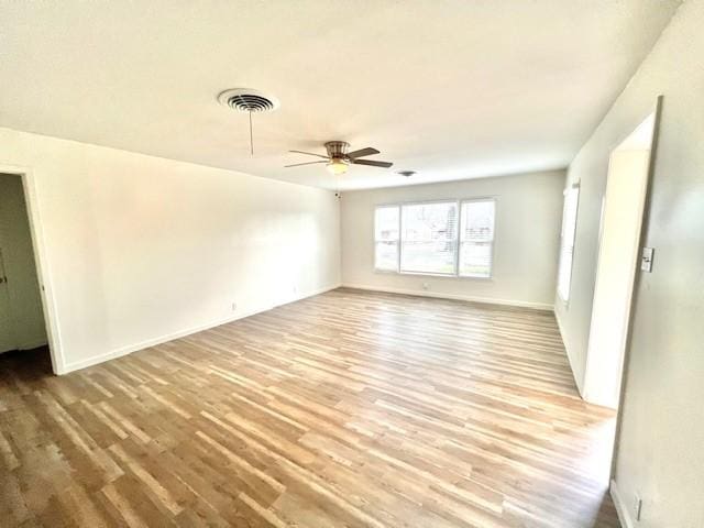 empty room with ceiling fan, wood finished floors, visible vents, and baseboards