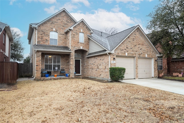 traditional-style home with driveway, brick siding, an attached garage, and fence