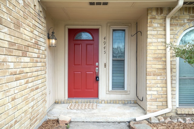 entrance to property featuring visible vents and brick siding