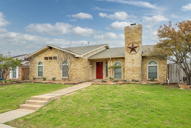 view of front of property with brick siding, a front lawn, a shingled roof, and fence