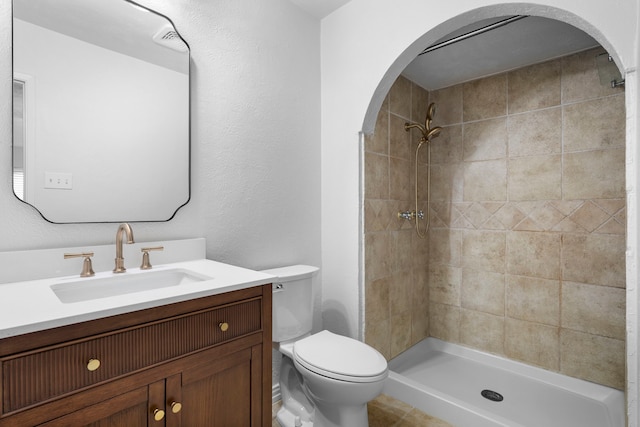 bathroom featuring tiled shower, vanity, and toilet