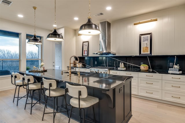 kitchen featuring dark countertops, visible vents, backsplash, and wall chimney exhaust hood