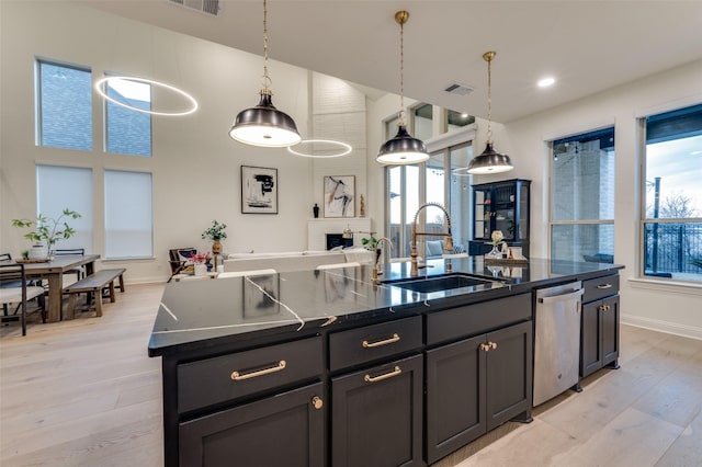 kitchen featuring a sink, dark countertops, dishwasher, and open floor plan