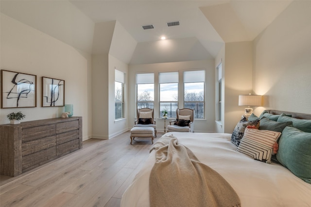 bedroom featuring light wood finished floors, visible vents, lofted ceiling, and baseboards