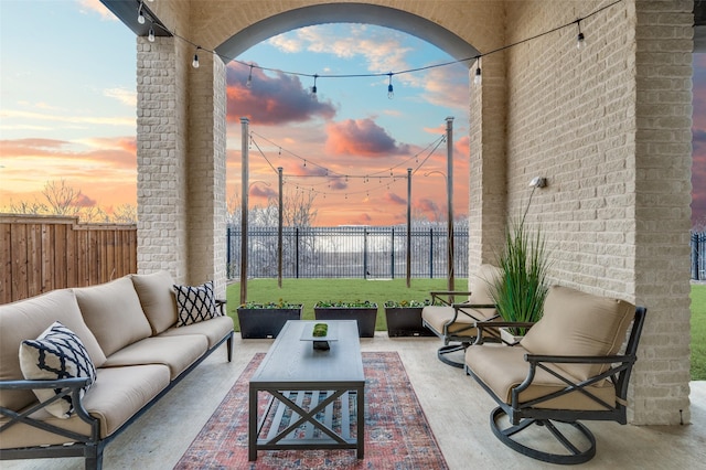 patio terrace at dusk featuring a lawn, outdoor lounge area, and a fenced backyard