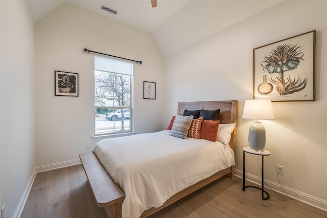 bedroom with visible vents, baseboards, wood finished floors, and vaulted ceiling