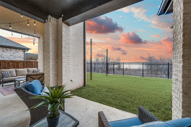 patio terrace at dusk featuring a lawn, a fenced backyard, and an outdoor hangout area