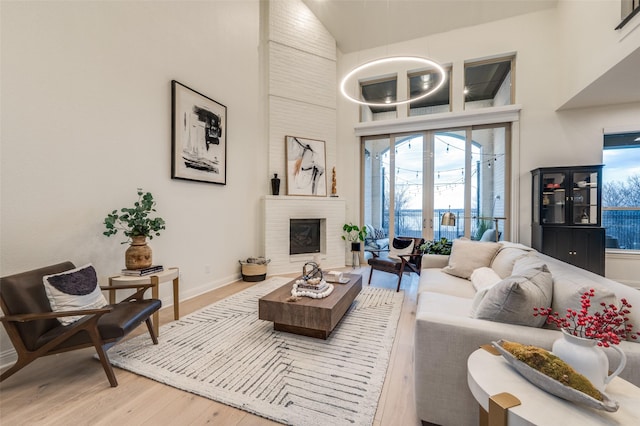 living area with a fireplace, a high ceiling, baseboards, and wood finished floors