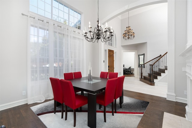 dining space featuring a chandelier, stairway, wood finished floors, and a towering ceiling