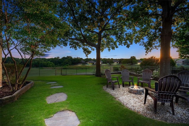 yard at dusk with an outdoor fire pit and fence