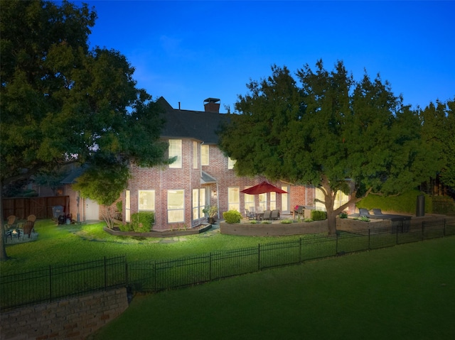 exterior space with a front yard, a fenced backyard, brick siding, and a chimney