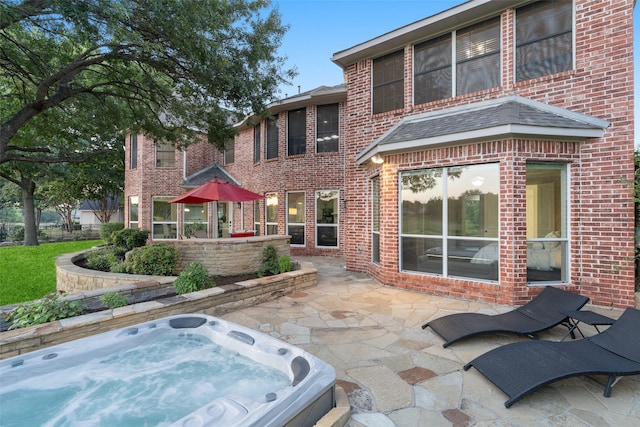 back of property with hot tub deck surround, brick siding, and a patio