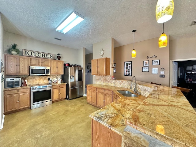 kitchen featuring a peninsula, a sink, hanging light fixtures, stainless steel appliances, and backsplash