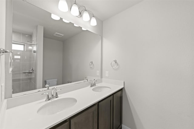 bathroom with toilet, double vanity, visible vents, and a sink