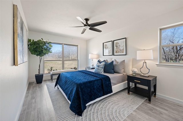 bedroom with ceiling fan, wood finished floors, and baseboards