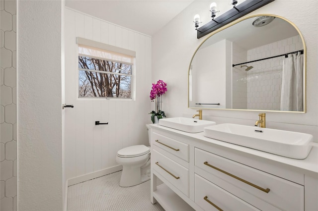 bathroom featuring toilet, a shower with curtain, double vanity, and a sink