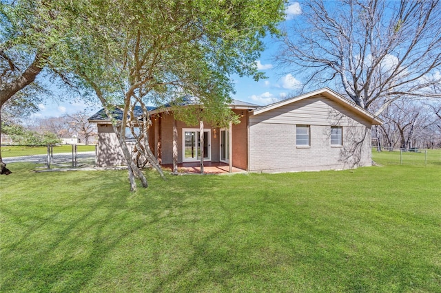 view of front facade with a front yard, fence, french doors, and brick siding