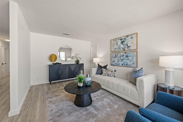 living area with wood finished floors, visible vents, and baseboards