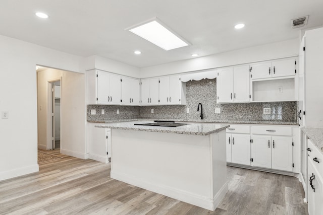 kitchen featuring visible vents, light wood-type flooring, white cabinetry, and decorative backsplash