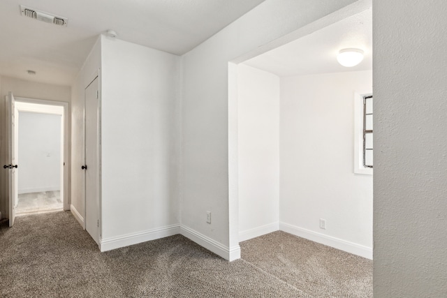 spare room featuring carpet floors, visible vents, and baseboards