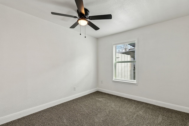 spare room featuring baseboards, dark carpet, and a ceiling fan